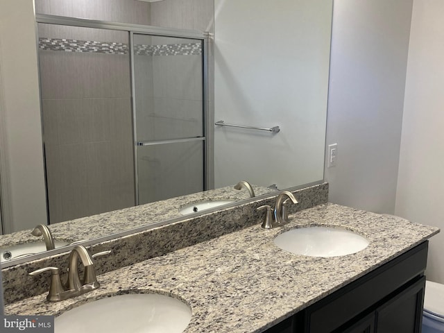 bathroom featuring a shower with door, vanity, and toilet