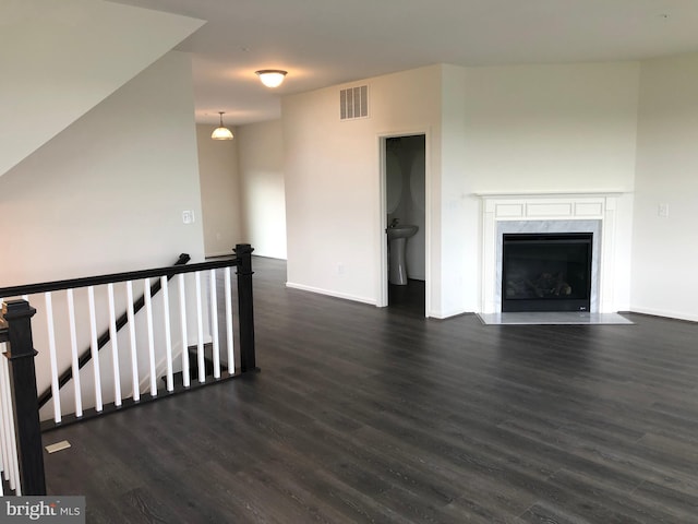 unfurnished living room featuring dark wood-type flooring and a high end fireplace