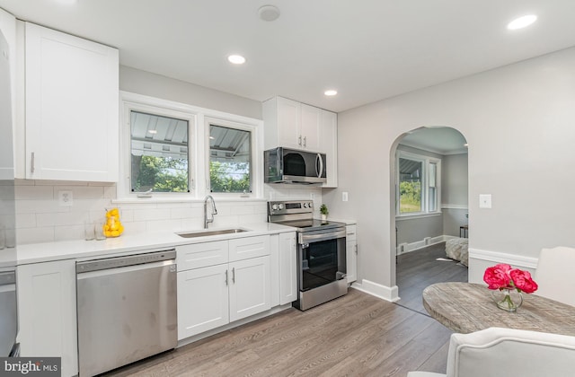 kitchen featuring sink, white cabinetry, stainless steel appliances, and light hardwood / wood-style flooring