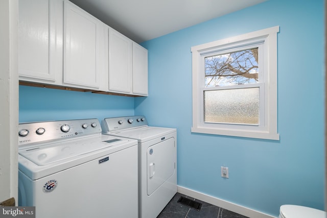 laundry room with cabinets, washing machine and dryer, and dark tile patterned floors