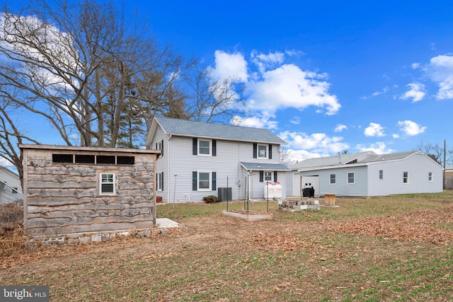 rear view of house featuring a yard, cooling unit, and an outbuilding