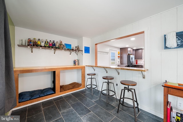 kitchen featuring a breakfast bar, kitchen peninsula, and stainless steel refrigerator with ice dispenser