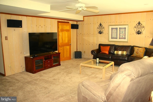 living room featuring carpet, wood walls, ceiling fan, and ornamental molding