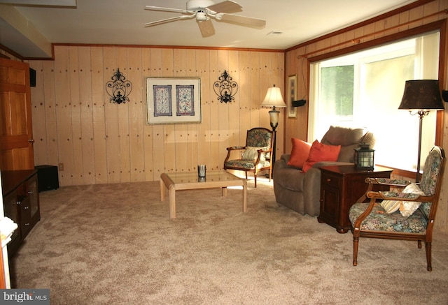 carpeted living room with ceiling fan, ornamental molding, and wooden walls