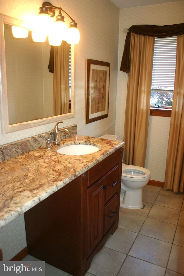 bathroom with toilet, vanity, and tile patterned floors