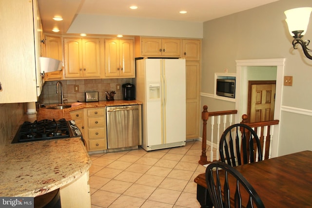 kitchen featuring light stone countertops, light brown cabinetry, backsplash, stainless steel appliances, and sink