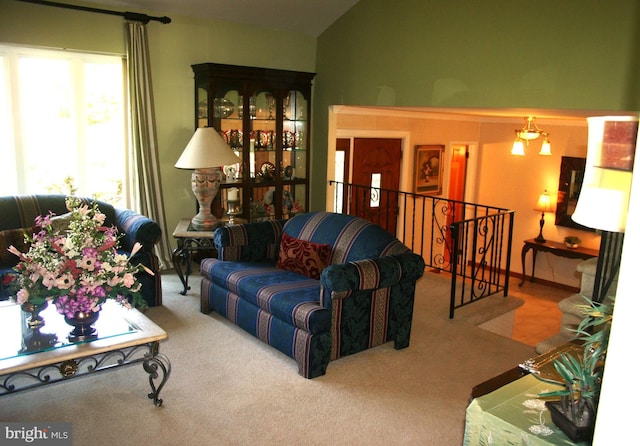 living room featuring carpet flooring, vaulted ceiling, and an inviting chandelier