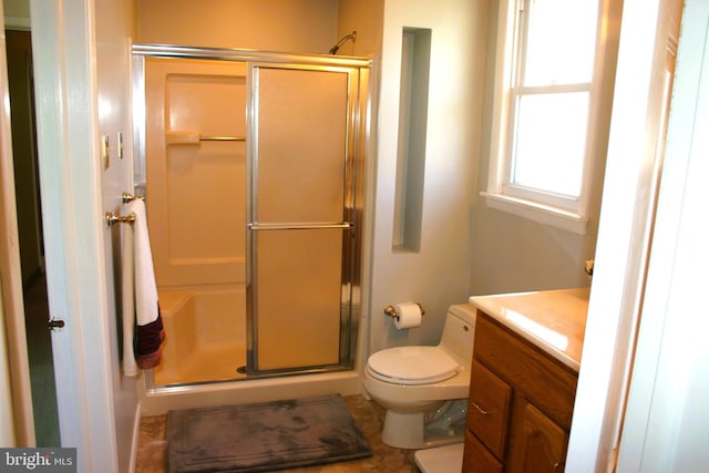 bathroom with vanity, toilet, and a shower with door