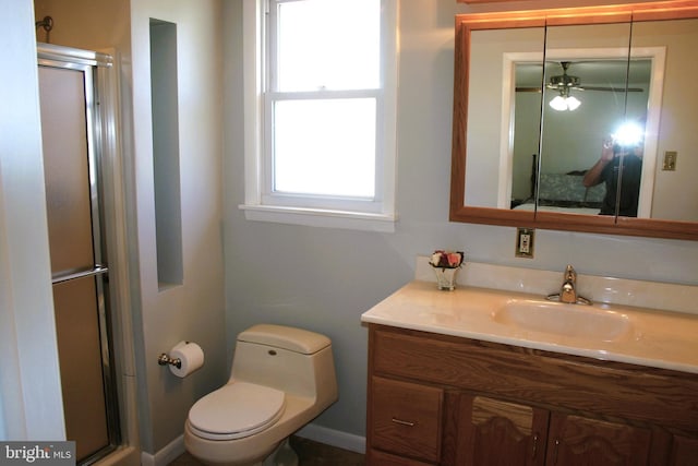 bathroom with ceiling fan, vanity, an enclosed shower, and toilet