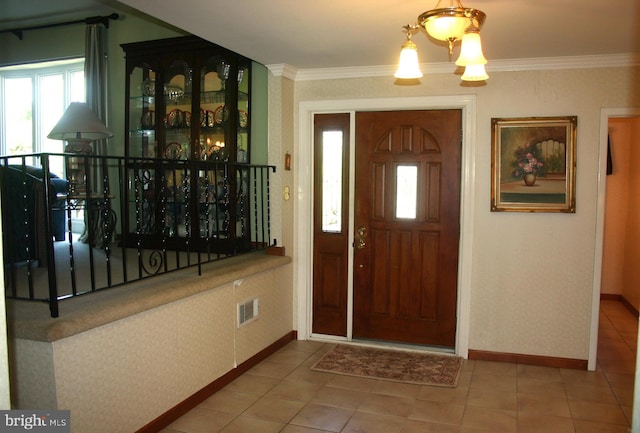 foyer featuring tile patterned floors, crown molding, and a chandelier