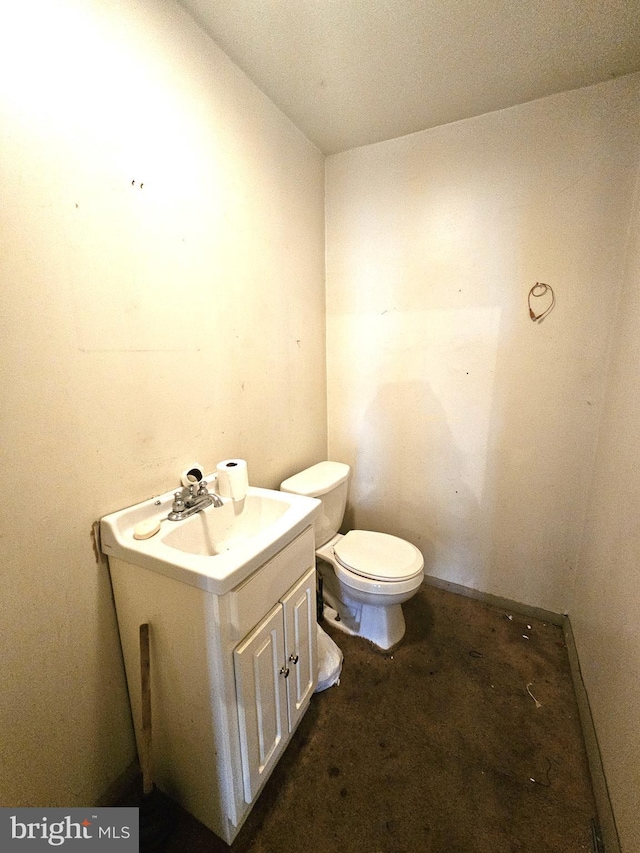 bathroom with concrete flooring, vanity, and toilet