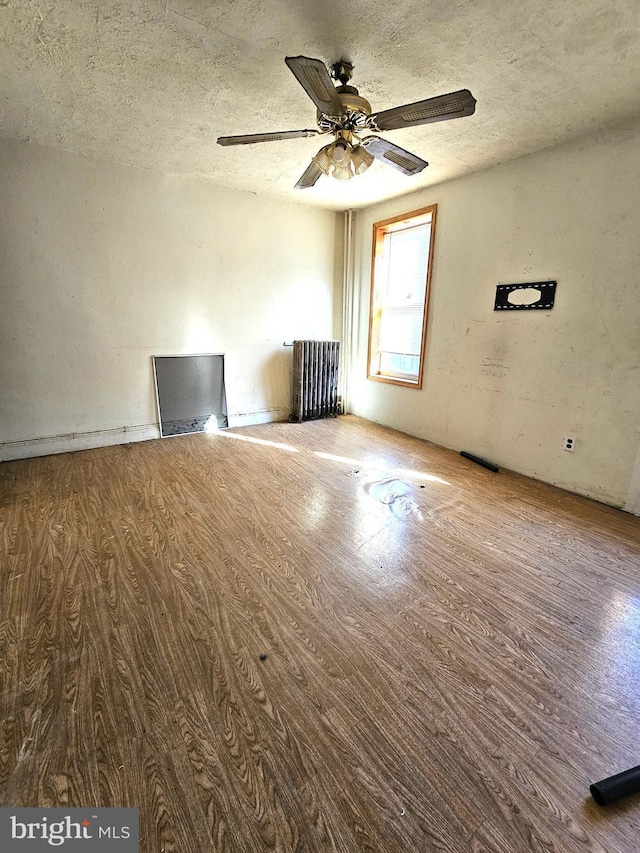 spare room with hardwood / wood-style floors, ceiling fan, and a textured ceiling