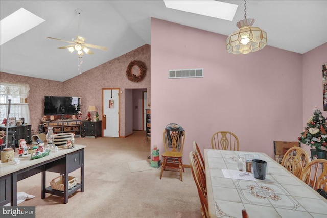 carpeted dining space featuring ceiling fan and vaulted ceiling with skylight