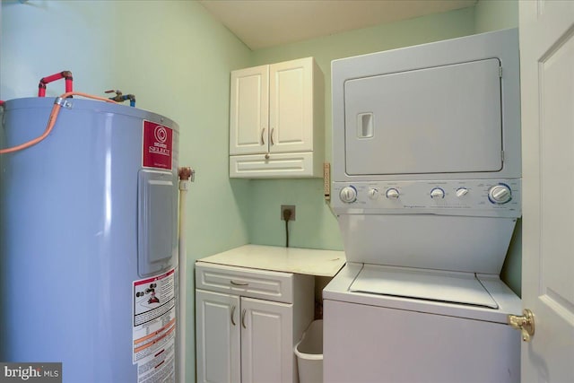 washroom with stacked washing maching and dryer, cabinets, and electric water heater