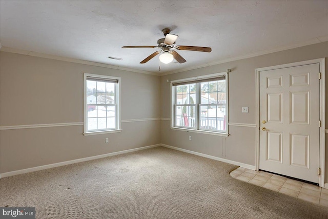 empty room with a wealth of natural light, light colored carpet, and ornamental molding