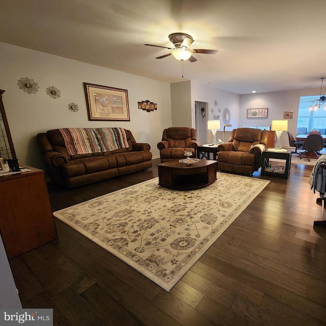 living room featuring ceiling fan with notable chandelier and dark hardwood / wood-style floors