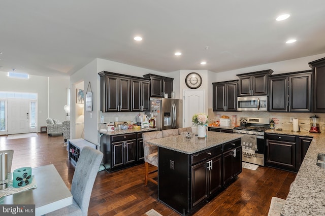 kitchen with light stone counters, dark wood-type flooring, stainless steel appliances, and tasteful backsplash