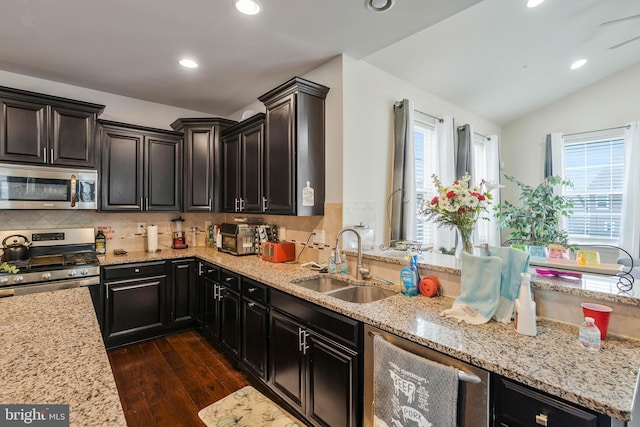 kitchen featuring backsplash, stainless steel appliances, vaulted ceiling, dark wood-type flooring, and sink