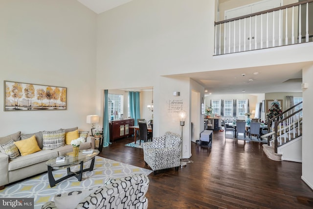 living room with a towering ceiling, dark wood-type flooring, and a wealth of natural light