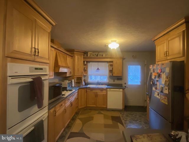 kitchen featuring light brown cabinetry, sink, custom exhaust hood, and appliances with stainless steel finishes