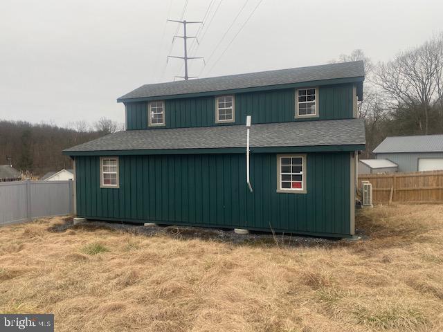 back of property featuring central AC unit and a yard