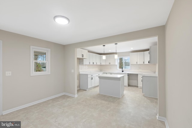 kitchen with sink, a kitchen island, tasteful backsplash, decorative light fixtures, and white cabinets