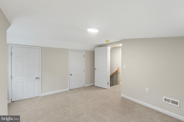 interior space featuring light carpet and vaulted ceiling