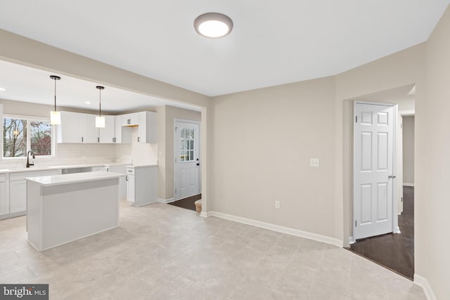 kitchen featuring tasteful backsplash, sink, pendant lighting, a center island, and white cabinetry