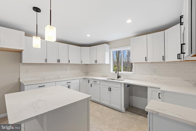 kitchen featuring white cabinets, a kitchen island, sink, and hanging light fixtures