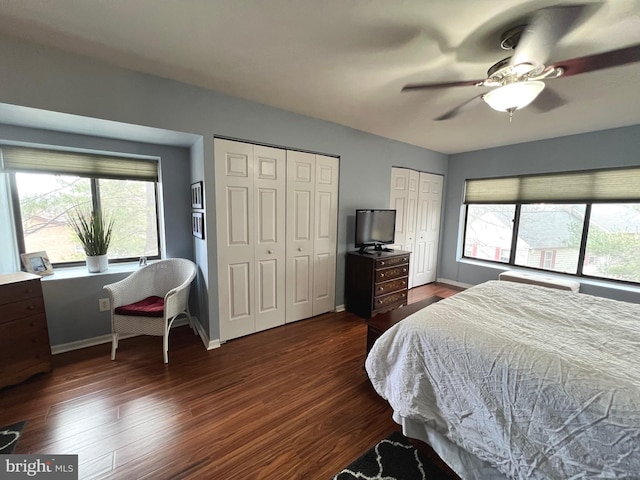 bedroom with ceiling fan, dark hardwood / wood-style floors, and two closets