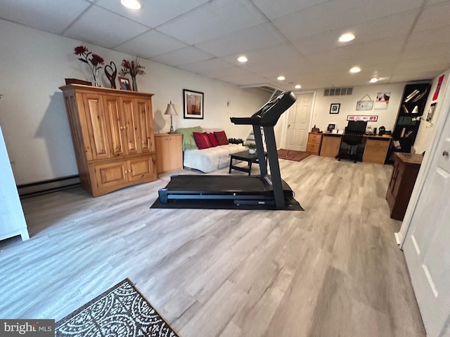 exercise room featuring a drop ceiling, light wood-type flooring, and a baseboard radiator