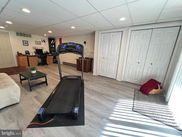 exercise room with wood-type flooring and a drop ceiling