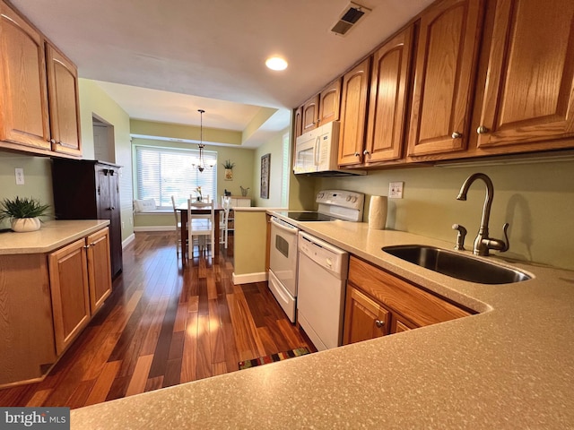 kitchen featuring sink, dark wood-type flooring, a notable chandelier, pendant lighting, and white appliances