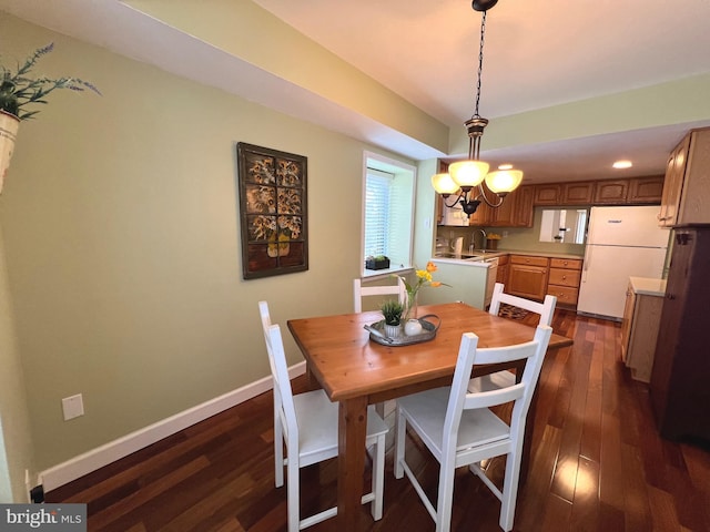 dining room with a notable chandelier, sink, and dark wood-type flooring