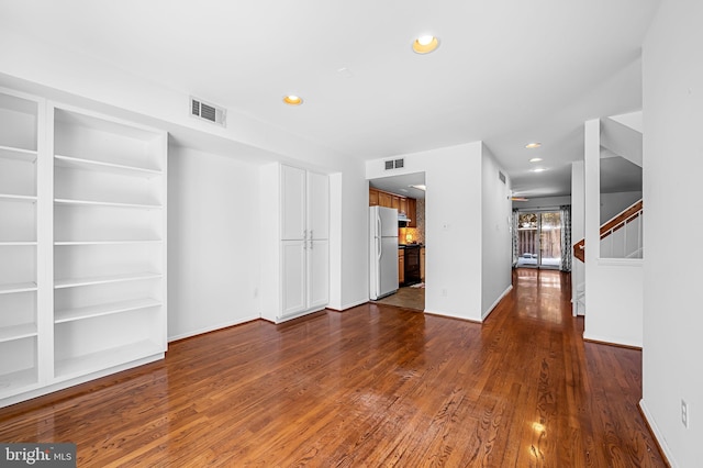 unfurnished living room featuring built in features and dark wood-type flooring