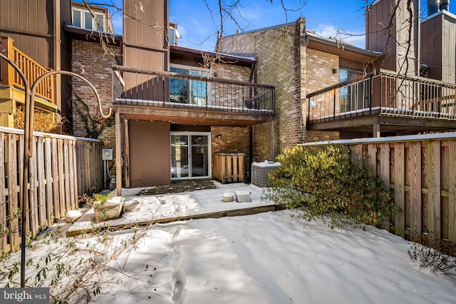 snow covered rear of property with a balcony and central air condition unit