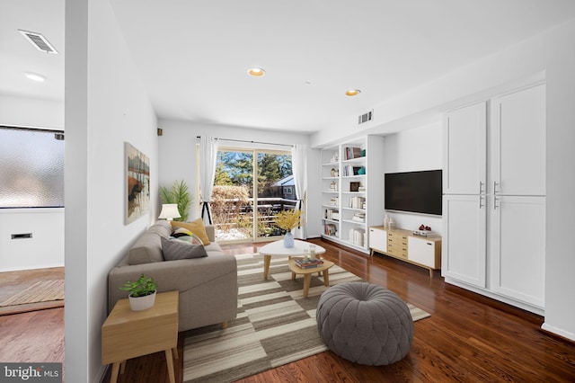 living room featuring built in shelves and dark hardwood / wood-style flooring