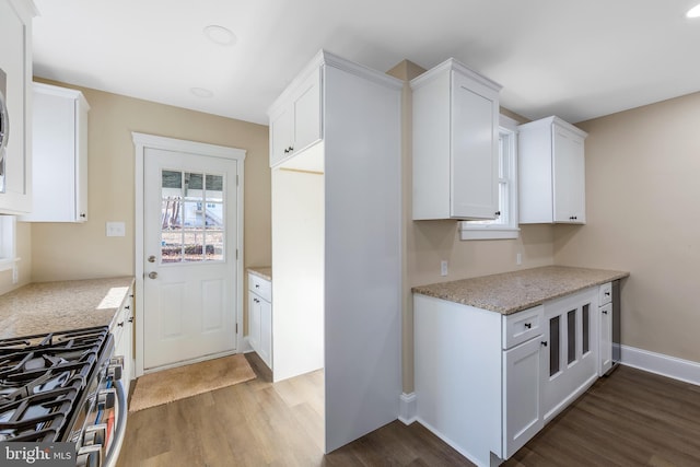 kitchen featuring white cabinets, dark hardwood / wood-style floors, gas stove, and light stone countertops