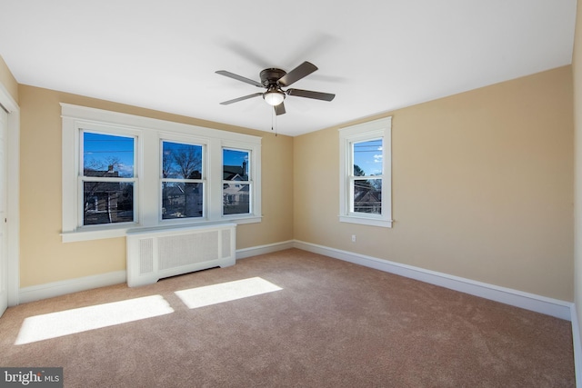 carpeted empty room featuring ceiling fan and radiator heating unit