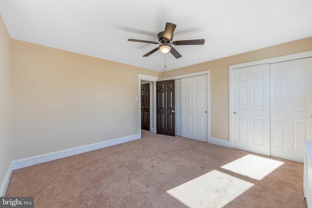 unfurnished bedroom featuring light colored carpet, ceiling fan, and multiple closets