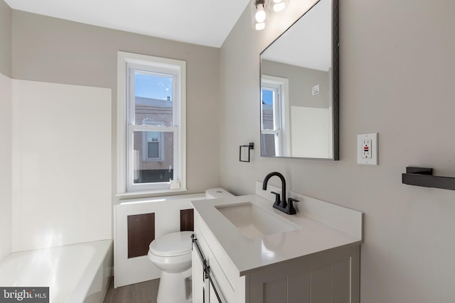 bathroom featuring a tub, vanity, wood-type flooring, and toilet