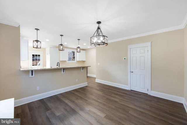 kitchen with a kitchen bar, kitchen peninsula, light stone countertops, white cabinets, and hanging light fixtures