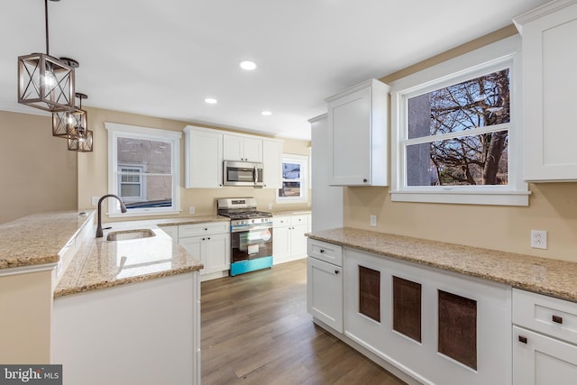 kitchen featuring pendant lighting, white cabinets, sink, and appliances with stainless steel finishes