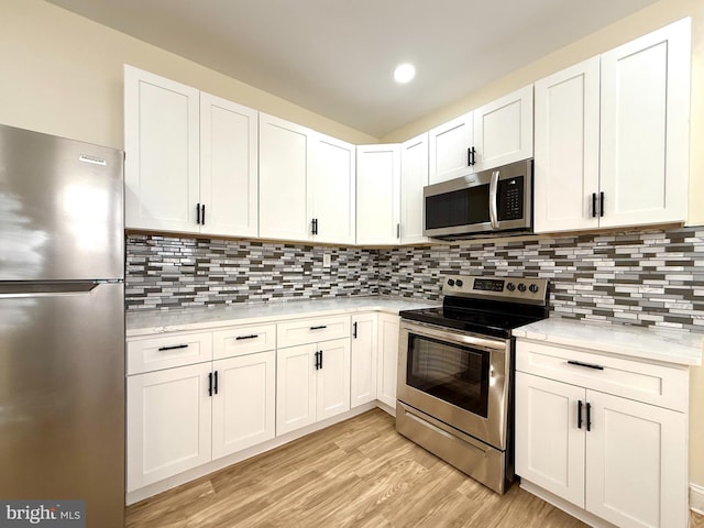 kitchen with light stone countertops, white cabinets, and stainless steel appliances