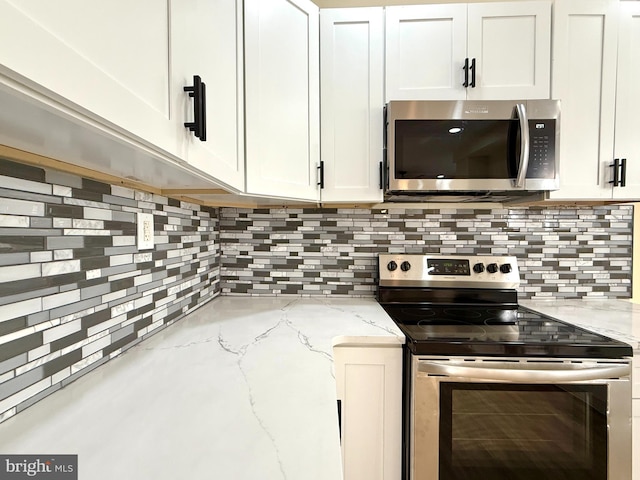 kitchen featuring white cabinets, appliances with stainless steel finishes, backsplash, and light stone countertops