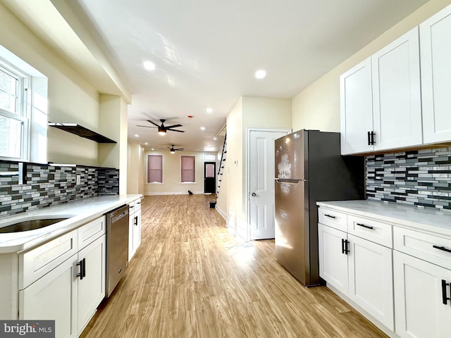 kitchen with white cabinets, appliances with stainless steel finishes, tasteful backsplash, and light hardwood / wood-style flooring