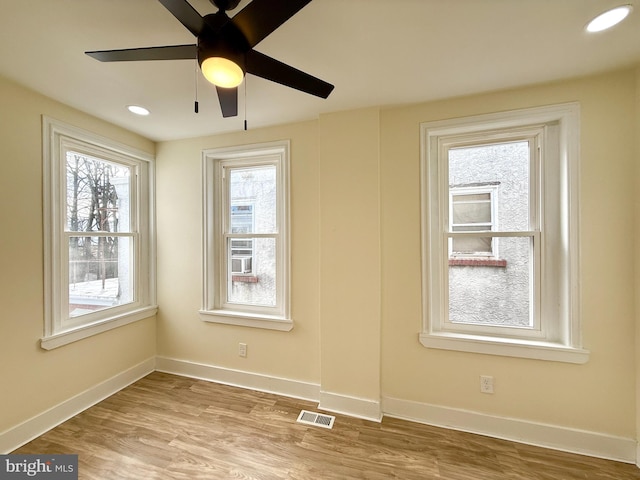 empty room featuring ceiling fan, plenty of natural light, and light hardwood / wood-style flooring