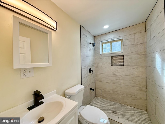 bathroom with vanity, toilet, and tiled shower