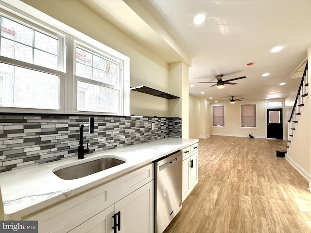 kitchen with dishwasher, sink, light stone countertops, light wood-type flooring, and white cabinetry