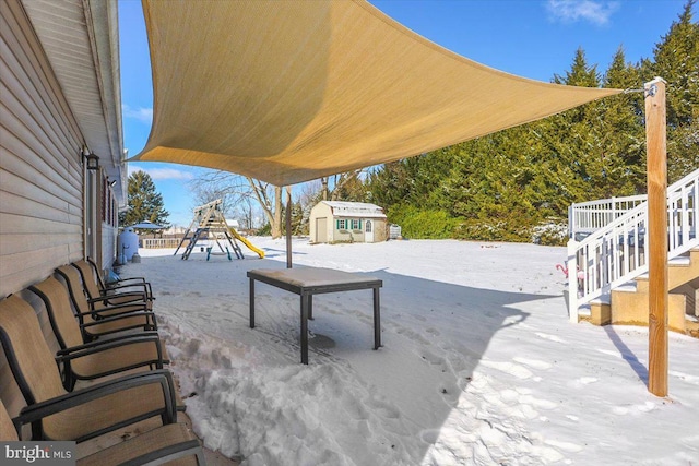 snow covered patio featuring an outbuilding and a playground